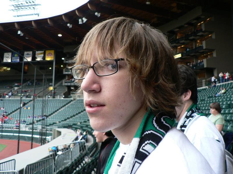 a boy wearing glasses and a scarf near an audience