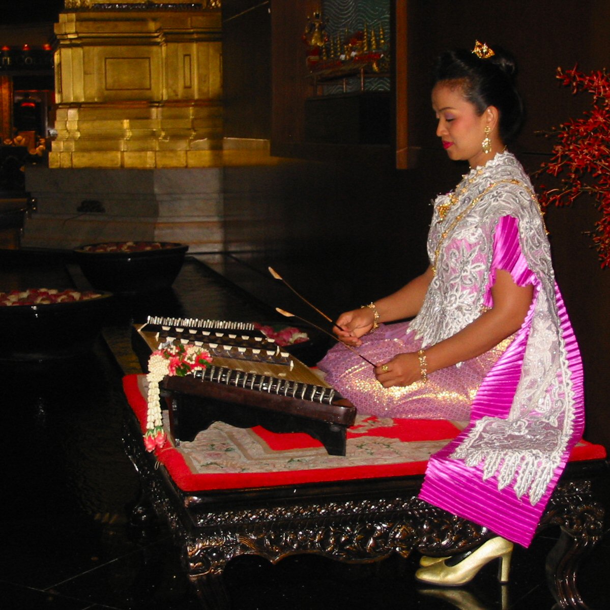 a woman in traditional thai garb holding a musical instrument