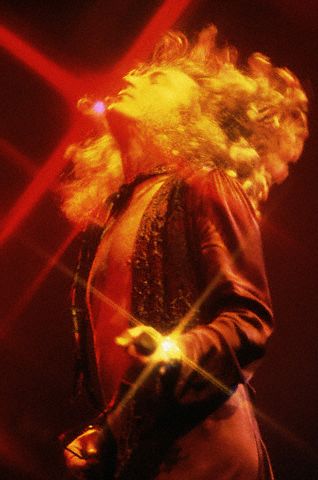 a man singing in front of red lights and on stage