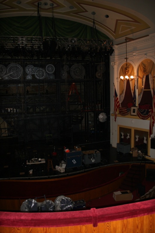 view from front stage of an auditorium, showing stage and screen with american flags