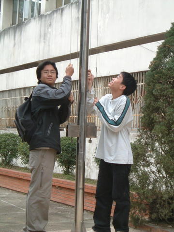 two people standing next to a pole with a phone