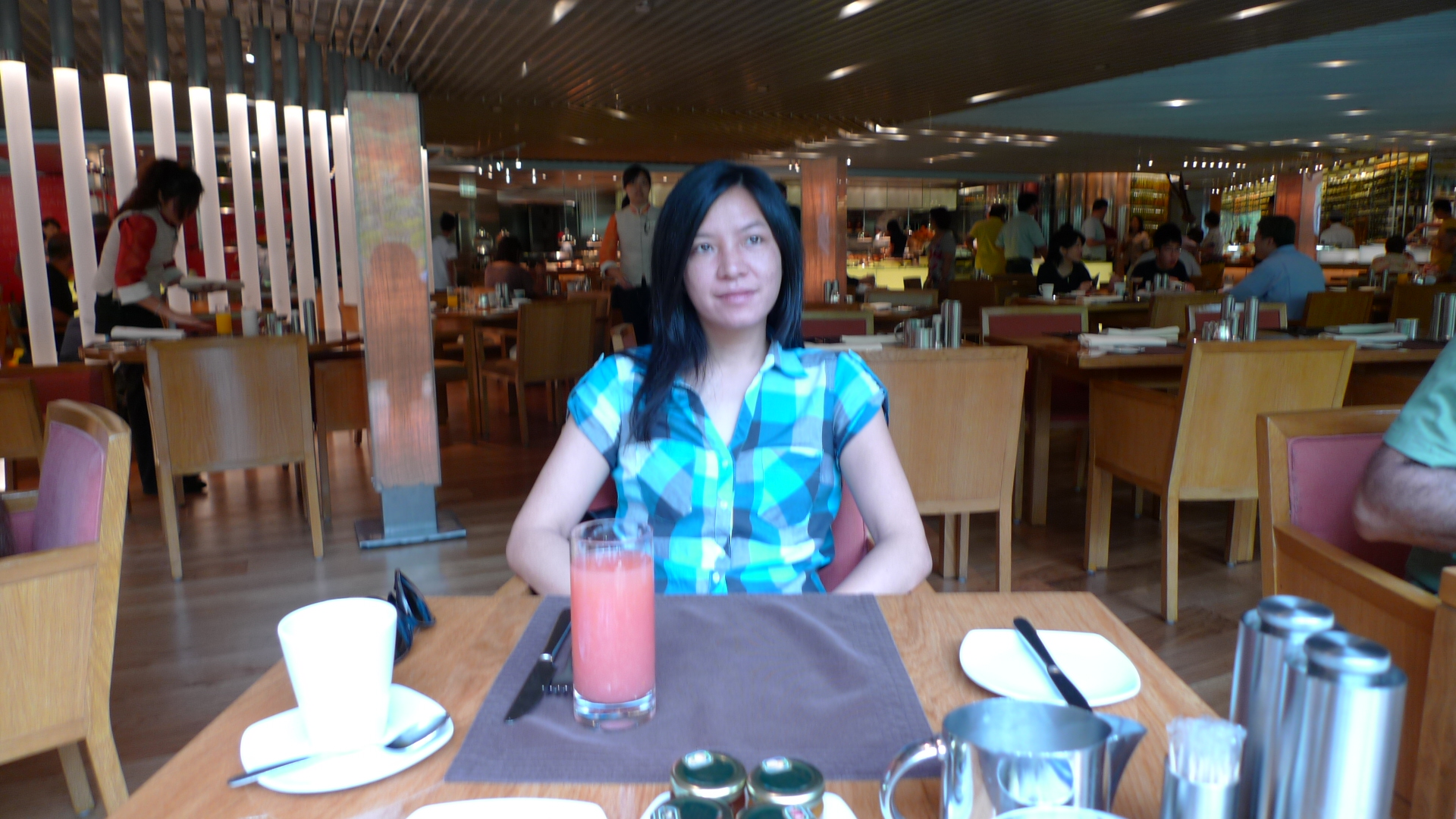 the woman sits in the dining area with a glass of red juice