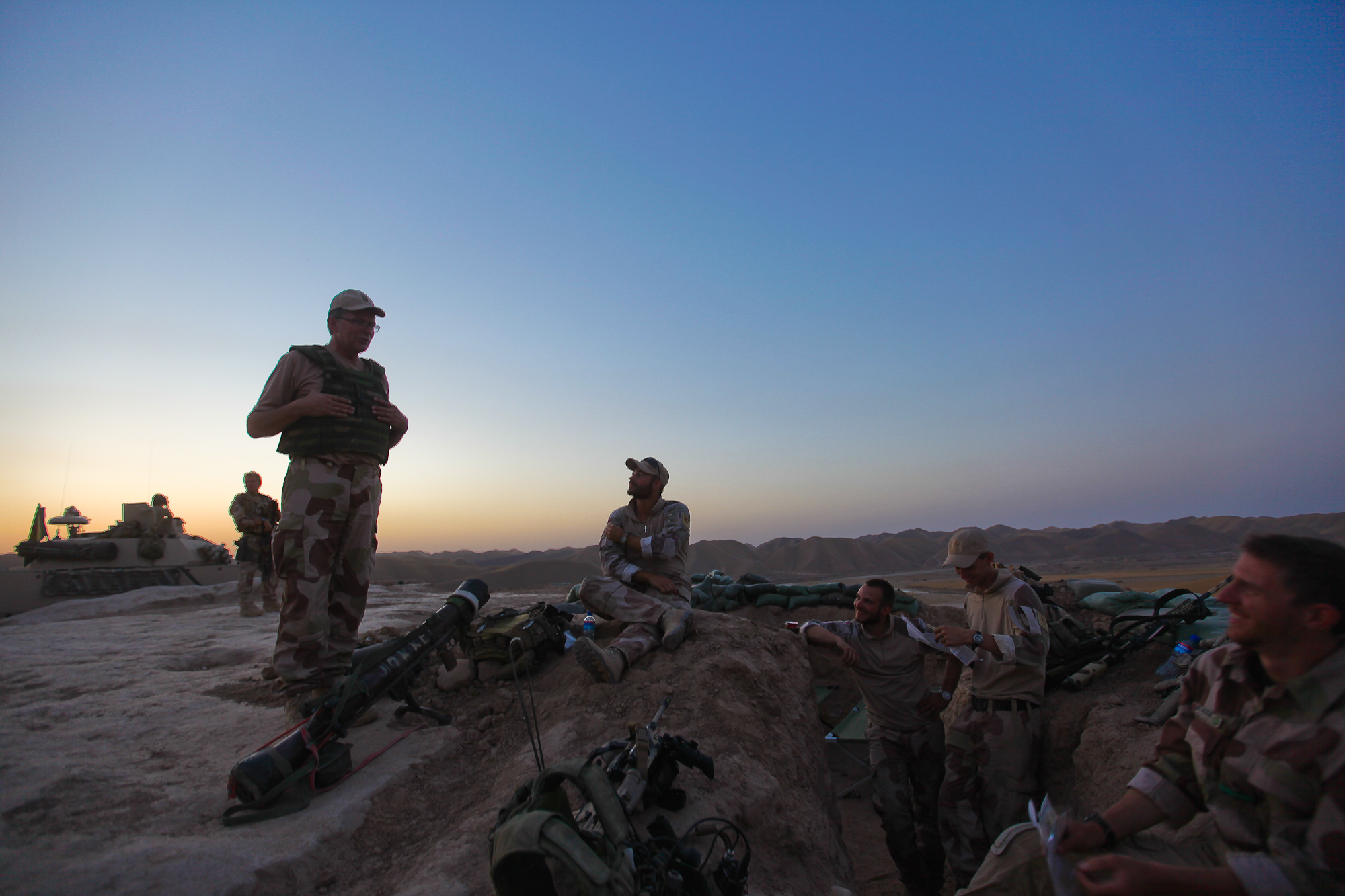 soldiers sit together near sleeping and backpacks in the desert