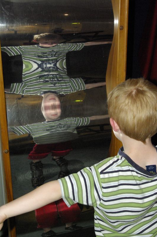 the little boy looks at an unusual image in a mirror