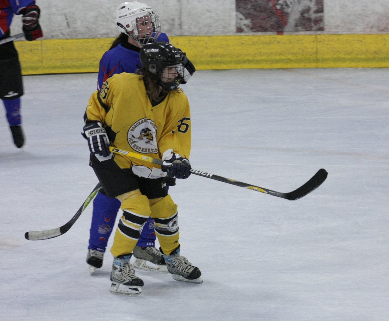 two girls playing hockey on an indoor rink