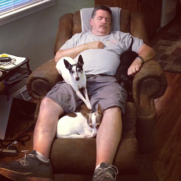 a man with two dogs sitting in his recliner