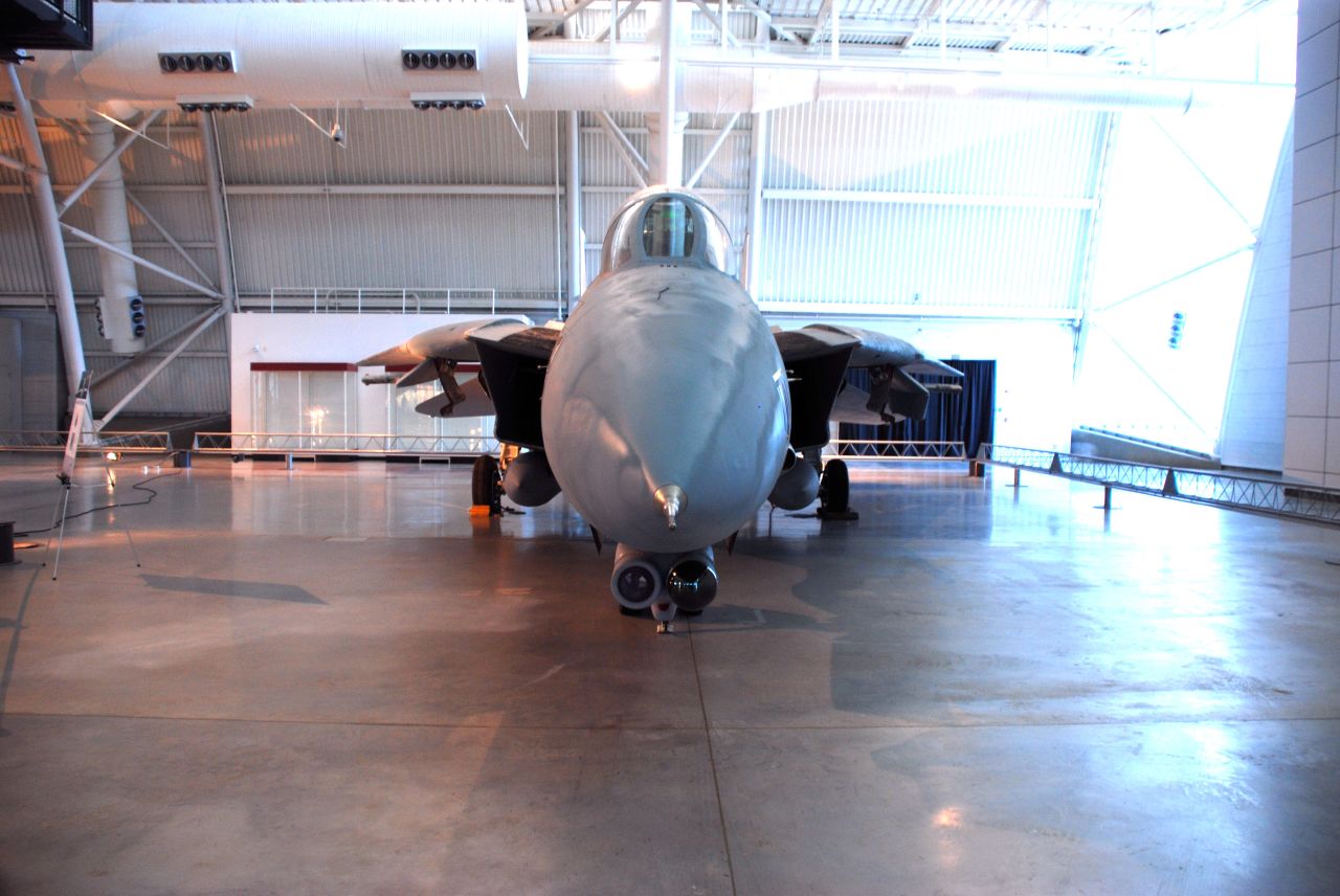 two jets sit parked in the hangar with a walkway behind them