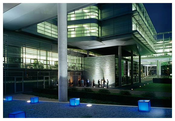 a group of people walk outside a building with blue lights