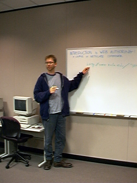 a man stands in front of a white board
