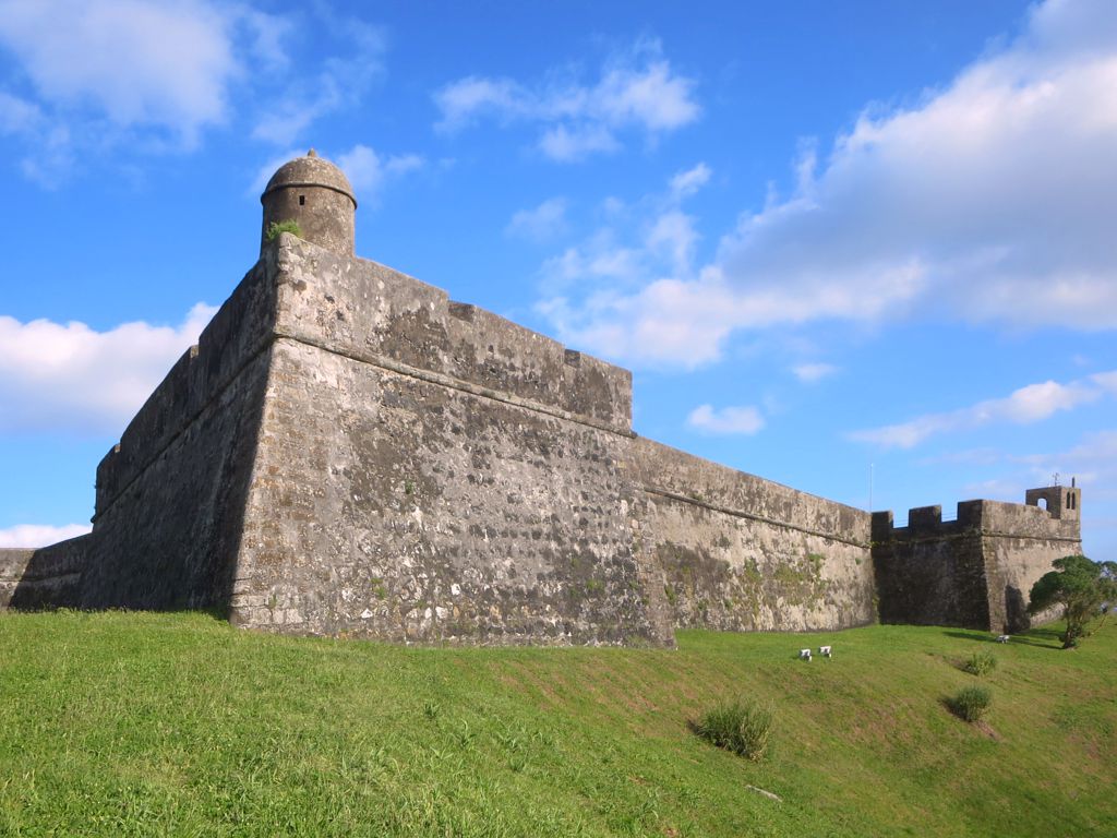 a large brick building sitting on top of a lush green hillside