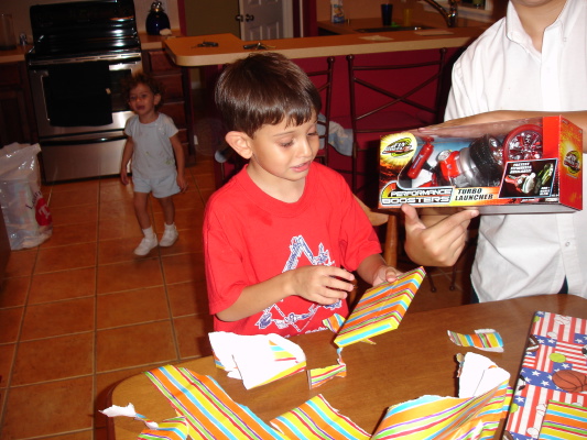 a man holding up a box of toys in front of a small boy