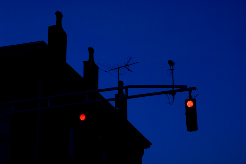 a dark city street with two red traffic lights