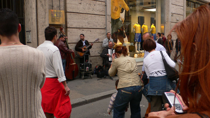 many people on a street near a store with guitars