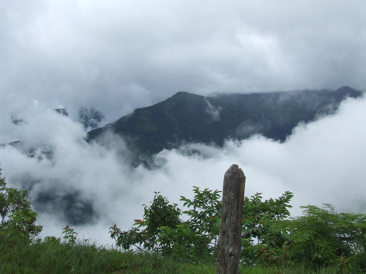 mountains covered in thick clouds and a fence post