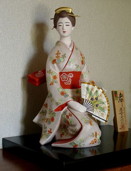 a figurine of an asian lady with an oriental fan sitting on a black table