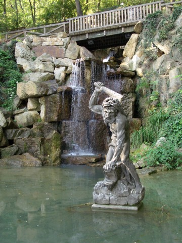 a stone sculpture is in front of a waterfall