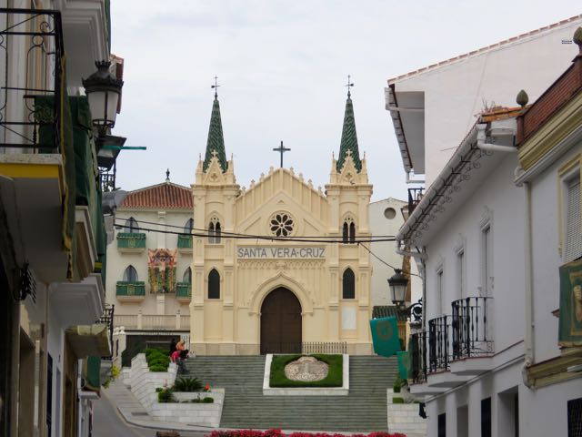 a very tall church surrounded by white and yellow buildings