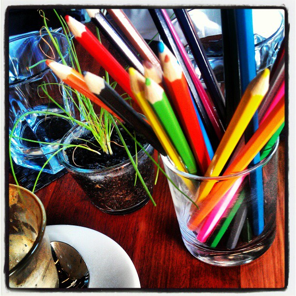 several colored pencils in a glass on a table