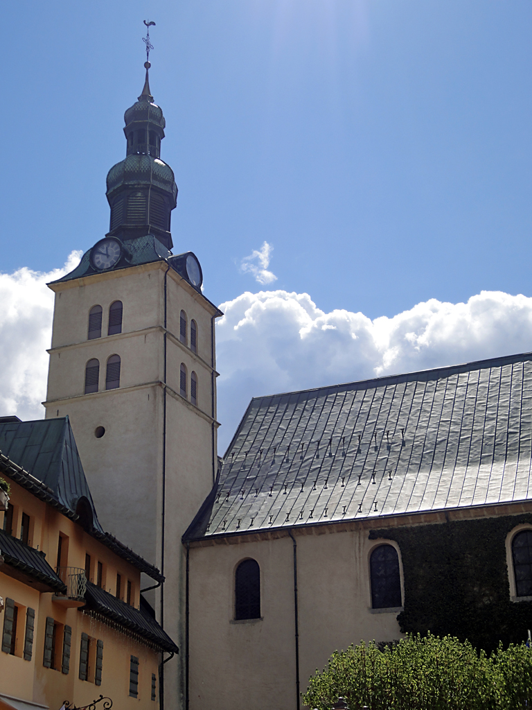 a white building with an steeple, two windows, and a large clock tower