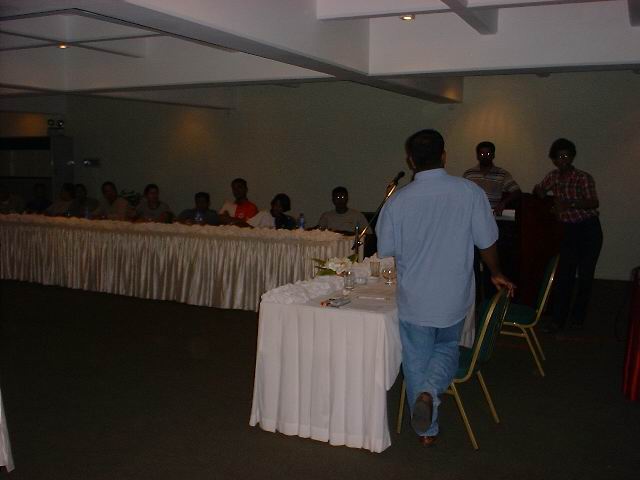 a man stands near a long table with white table cloth on it