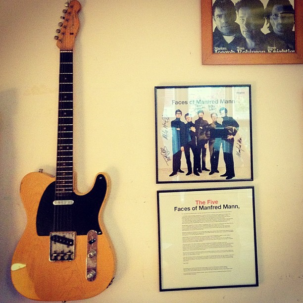an old guitar on display beside a plaque and pictures