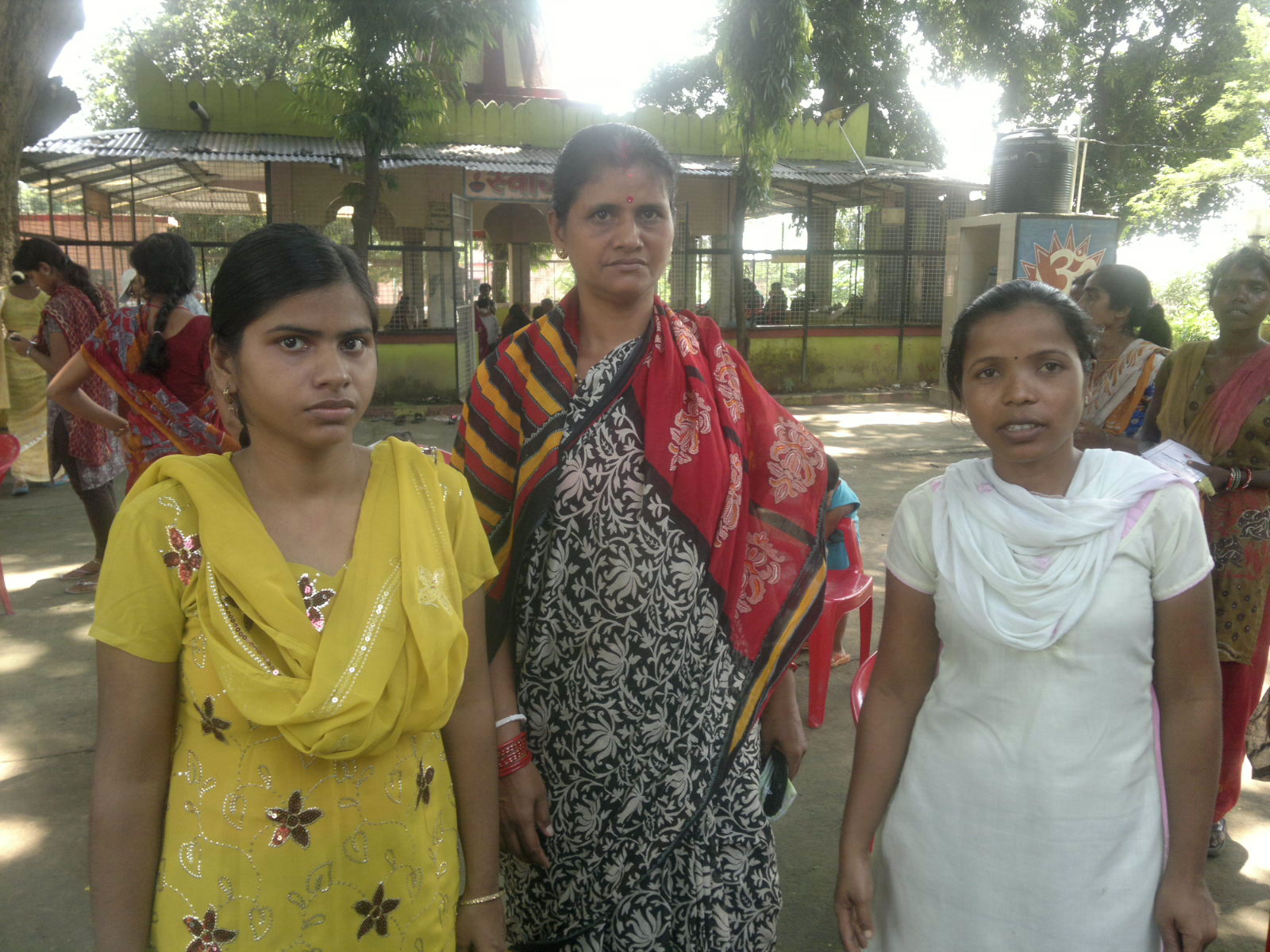 three women are posing for the camera with one woman in sari