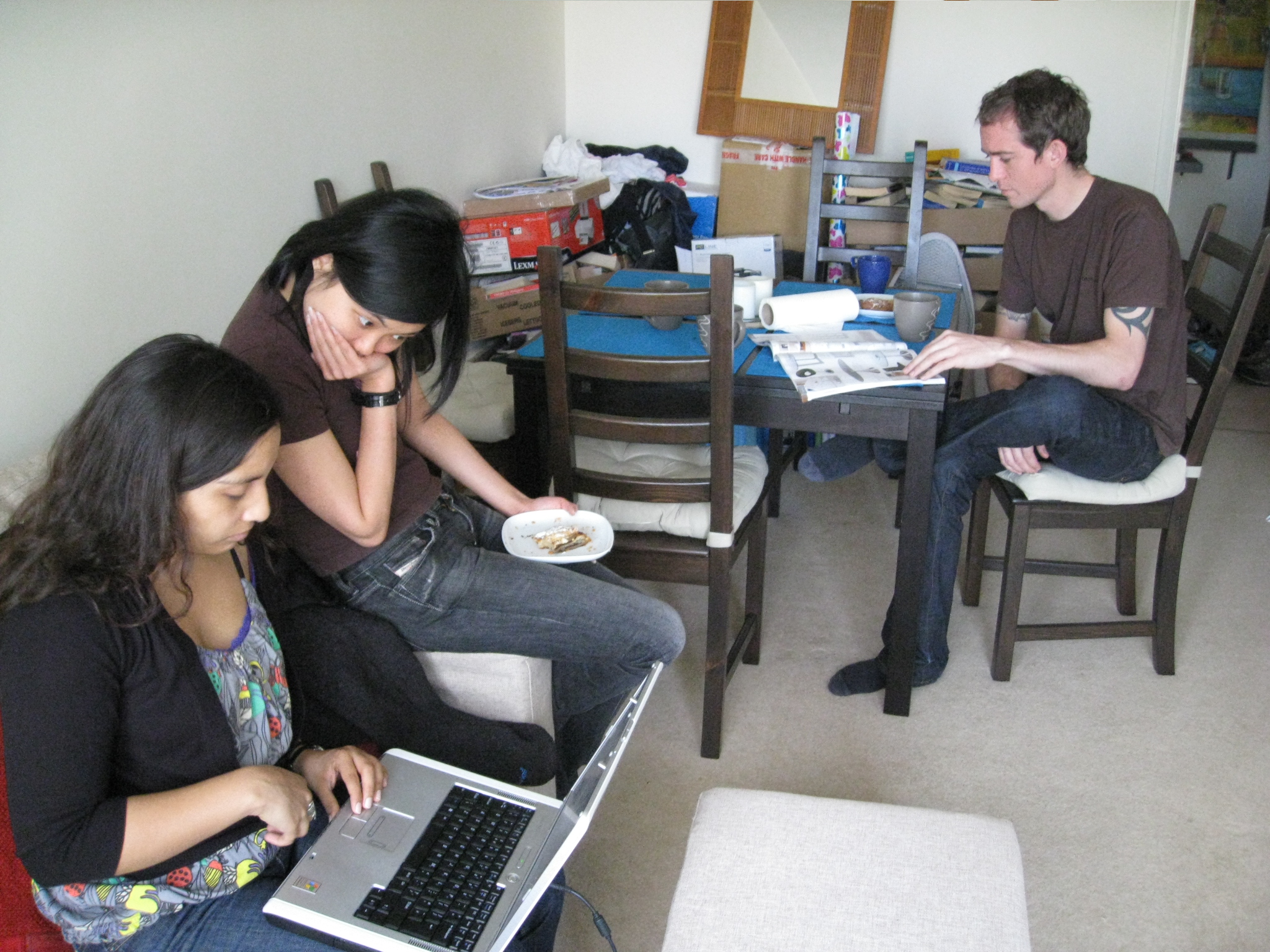 three people sitting at a table looking at their laptops
