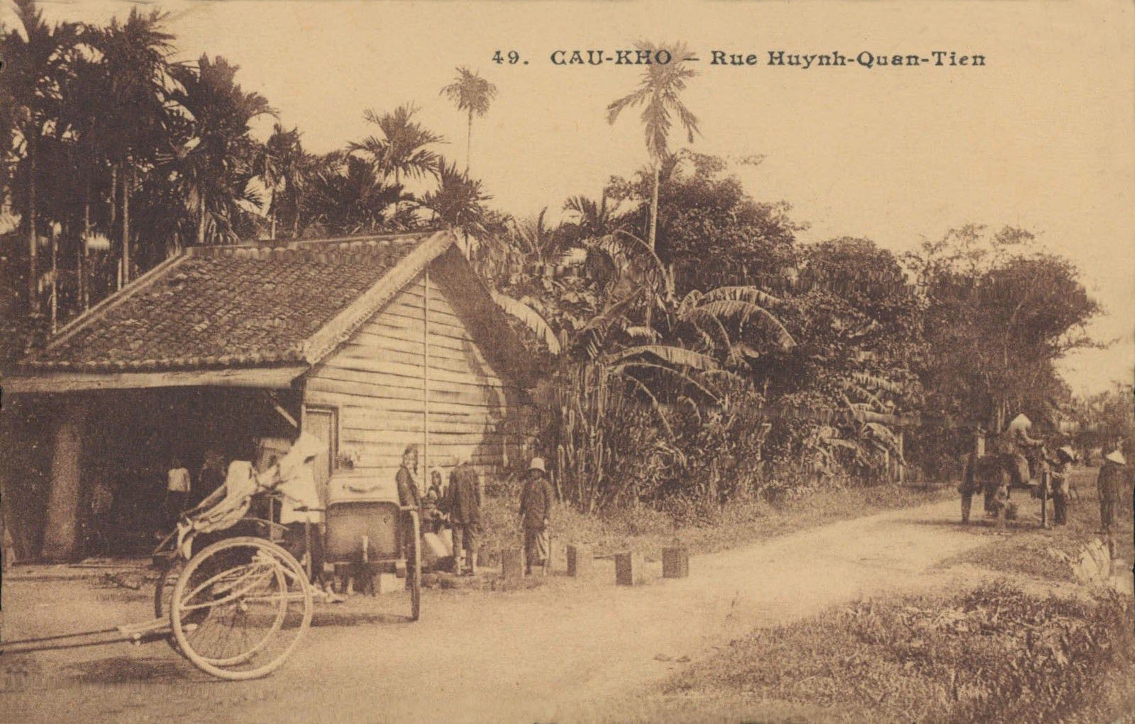 a sepia - toned pograph of an amish house with people riding on bicycles