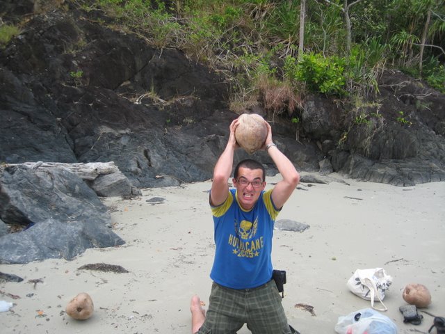 man holding up a rock and other items on the beach