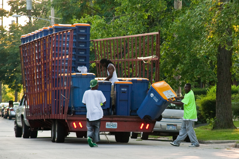 people unloading the truck with several blue bins