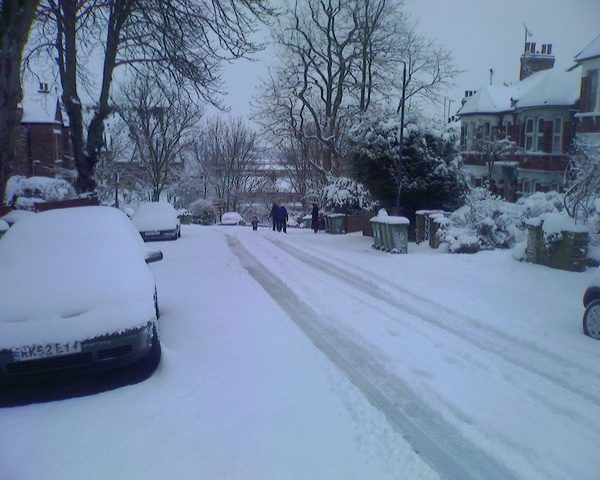 a couple of people walking down a snowy street
