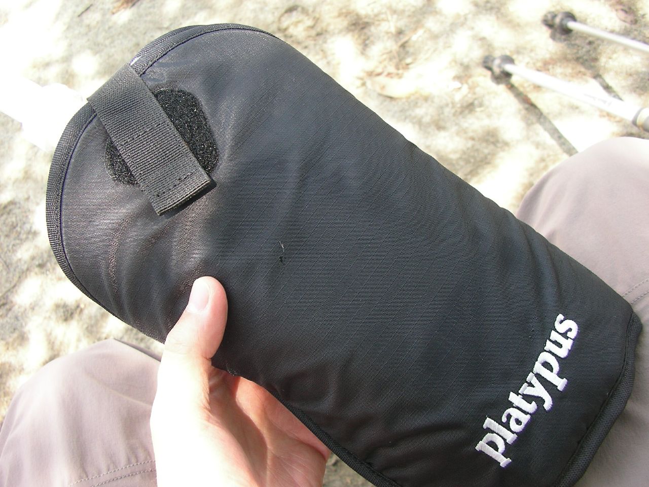 a black pouch in someones hand on the ground