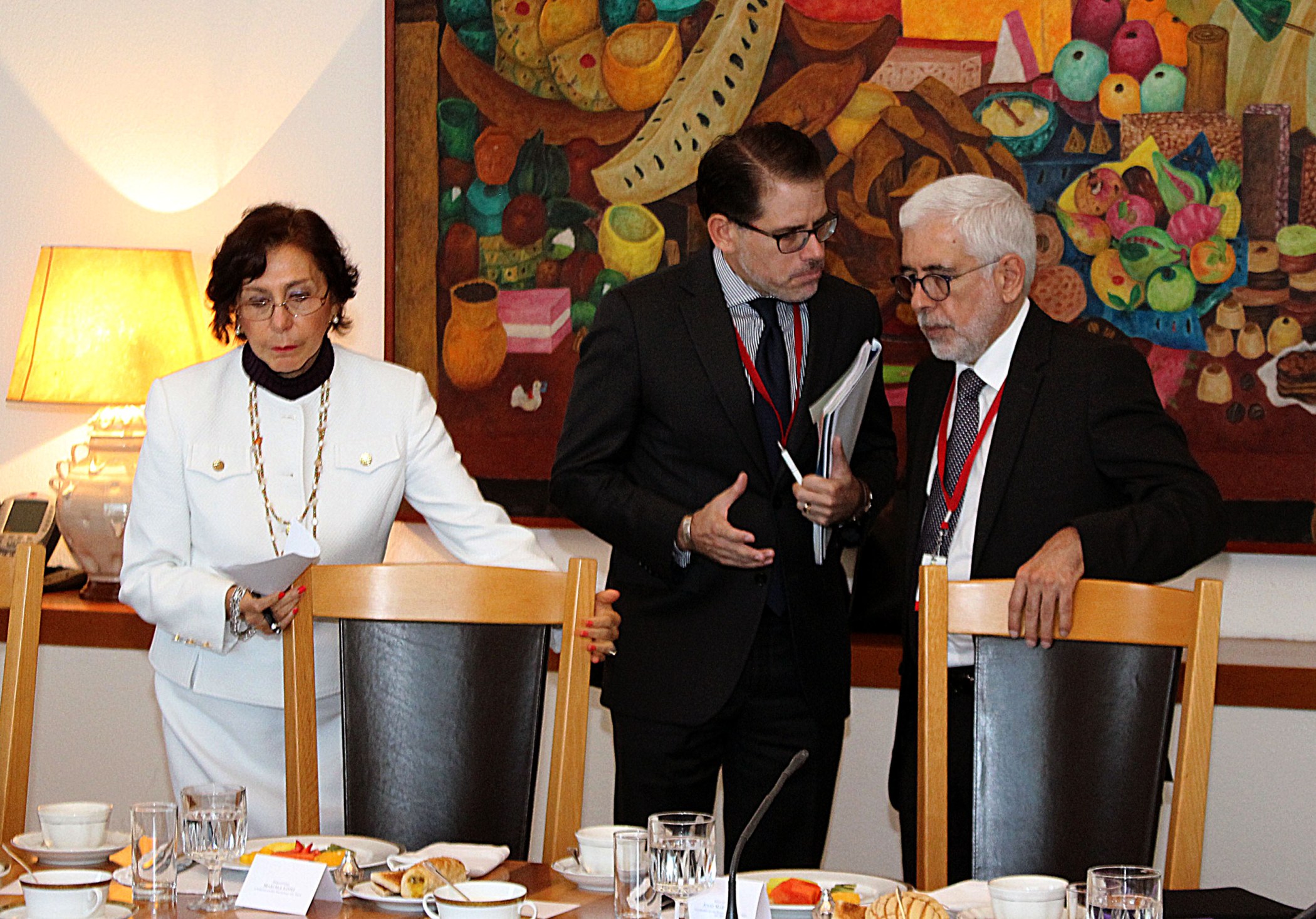 three people dressed in business suits stand around a dinner table