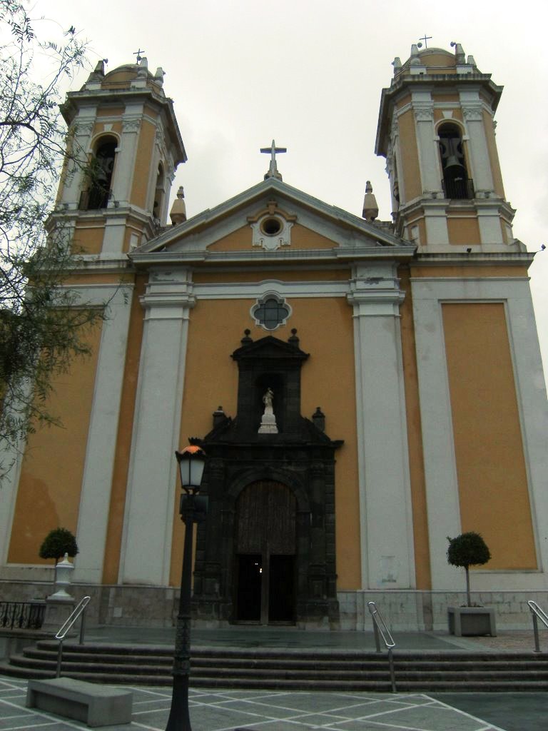 an old yellow church has two tall clocks