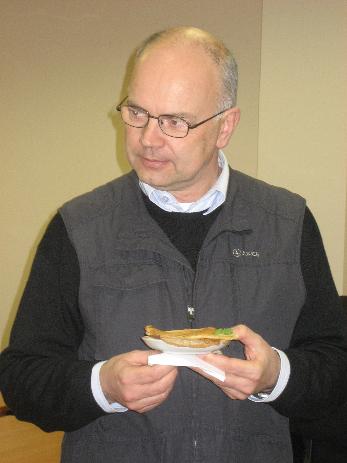 man in glasses eating a sandwich with paper