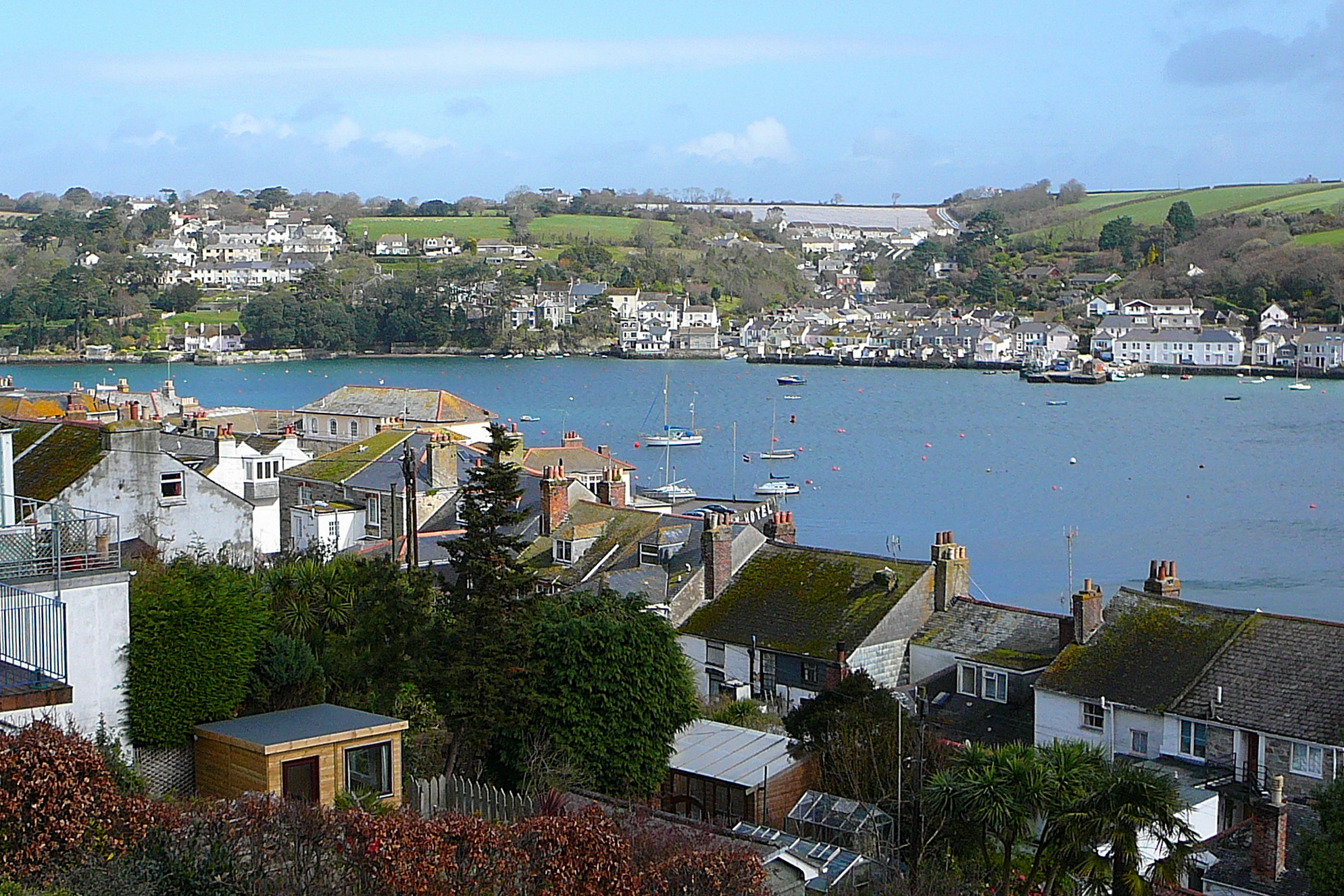 the view of boats out in the bay at a town on a hill