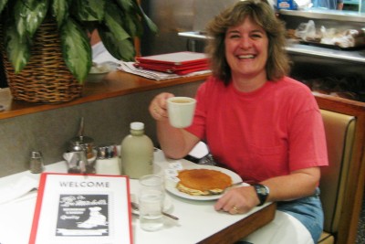 the woman is sitting in the booth with her plate of food