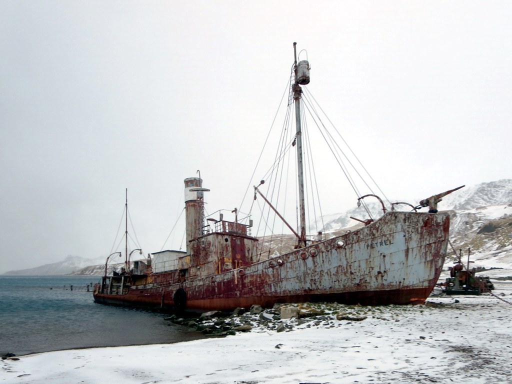 a old rusted ship sits in the ocean