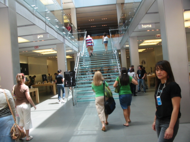 several people walk down a staircase in a shopping area