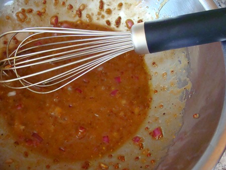 an orange sauce being whisked by a wire whisk