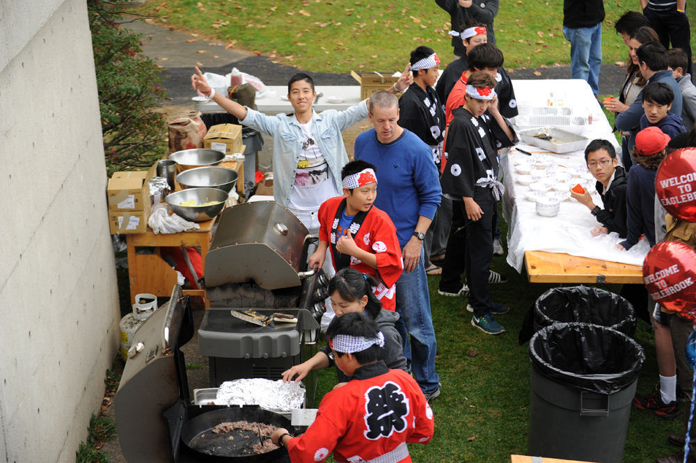 a group of people standing around an outdoor bbq