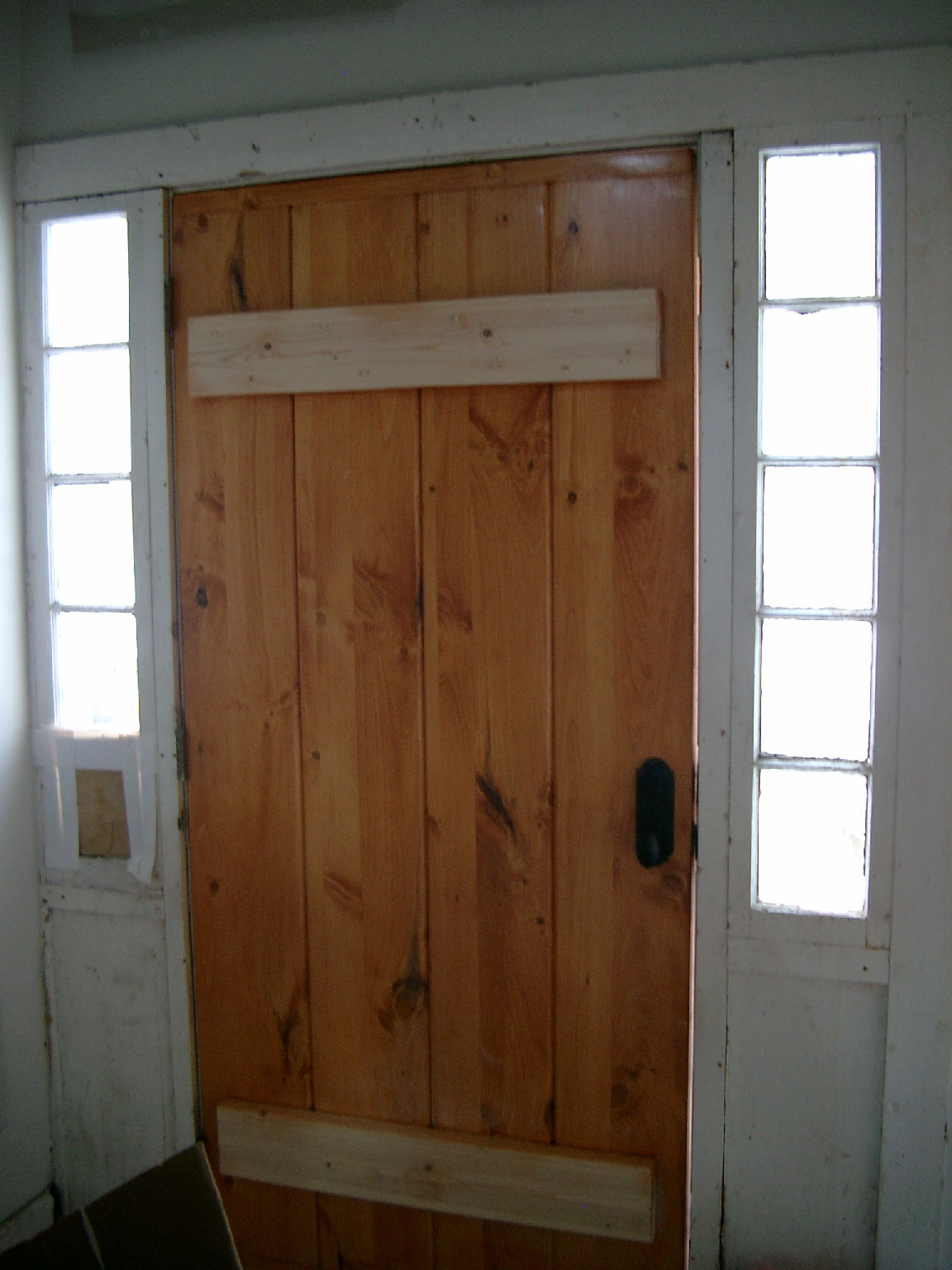 a wooden door with some windows and a lamp on