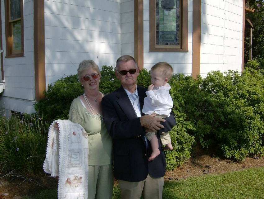 a man, woman and a child stand in front of a house