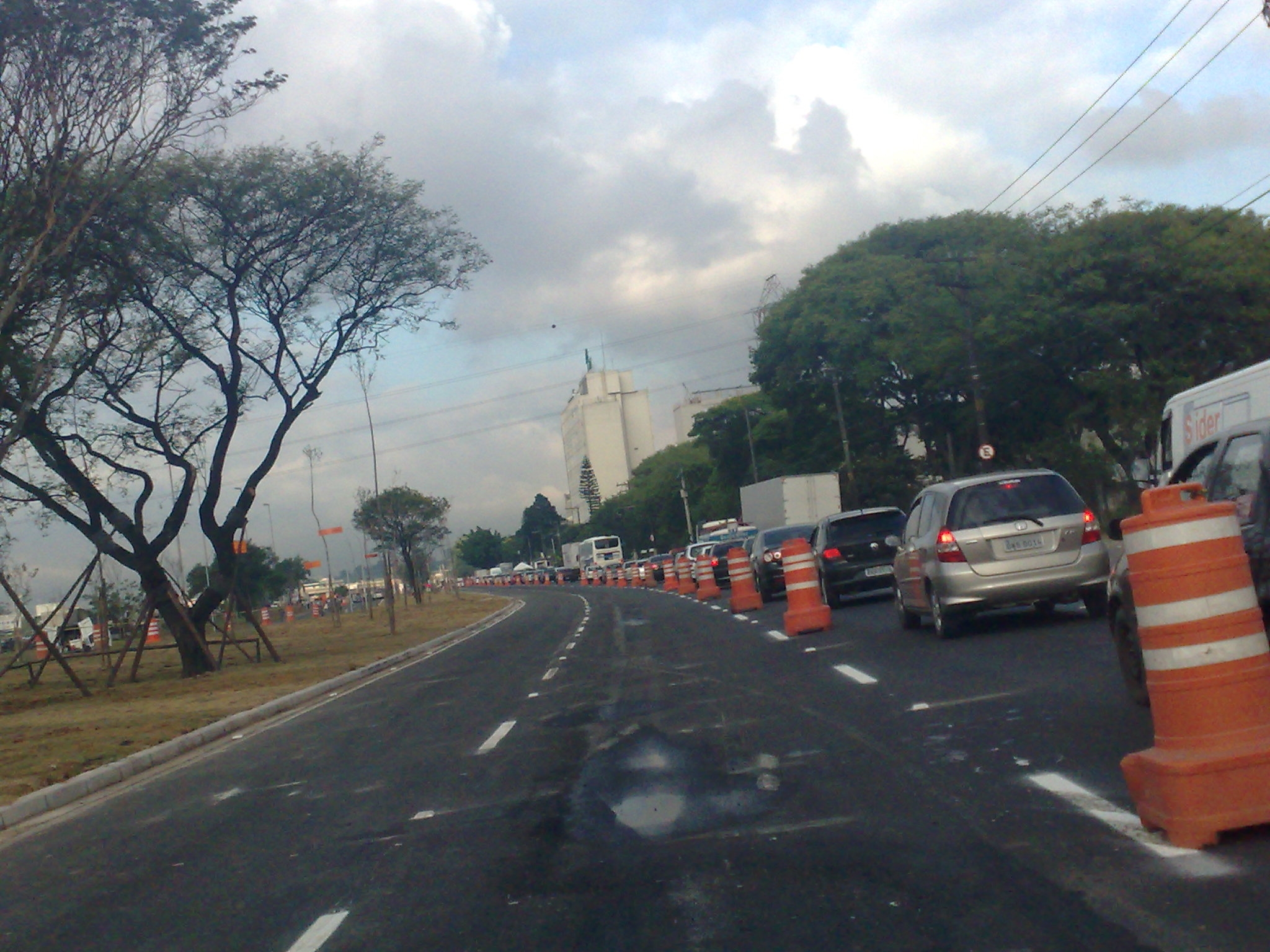 cars and a van driving down a road with orange traffic cones