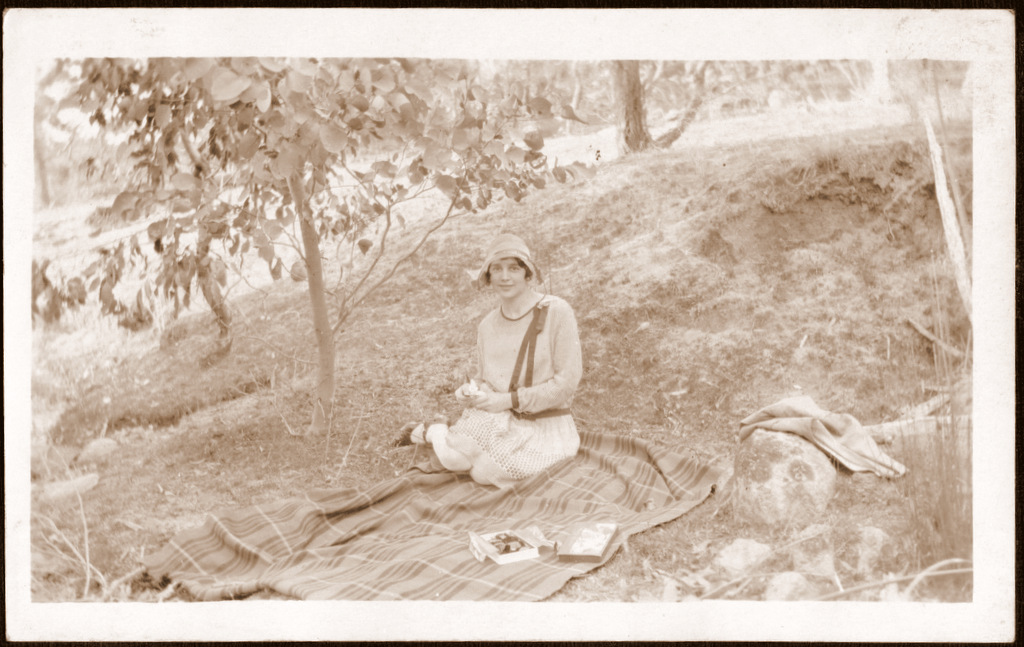 a woman sitting on a blanket in the woods