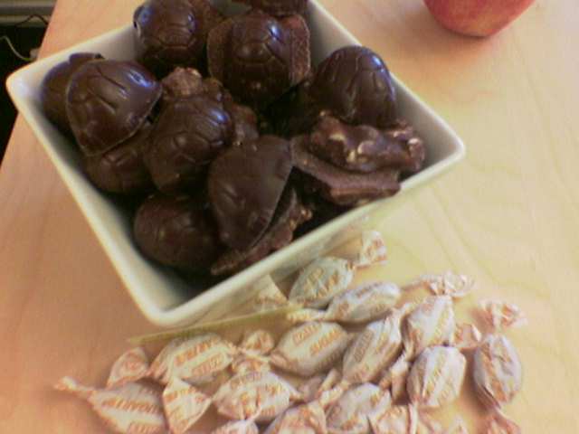 an assortment of almonds, chocolates and apples in bowls on a counter