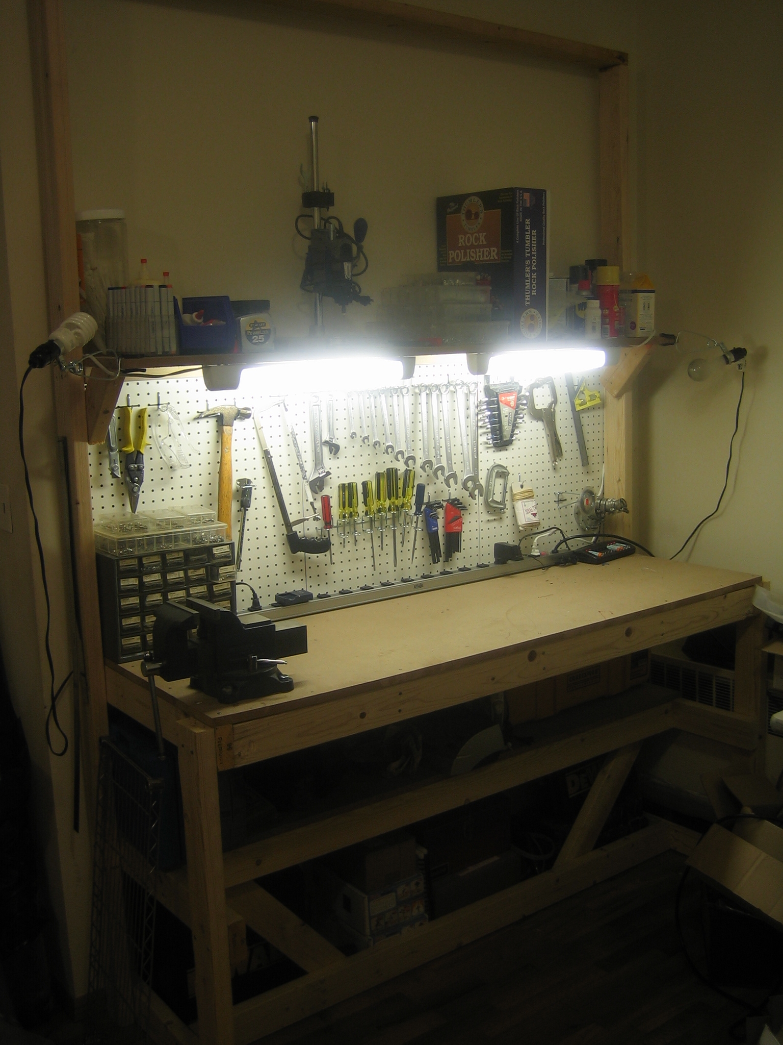 a work bench has multiple pegs all over it and is lit up with a light