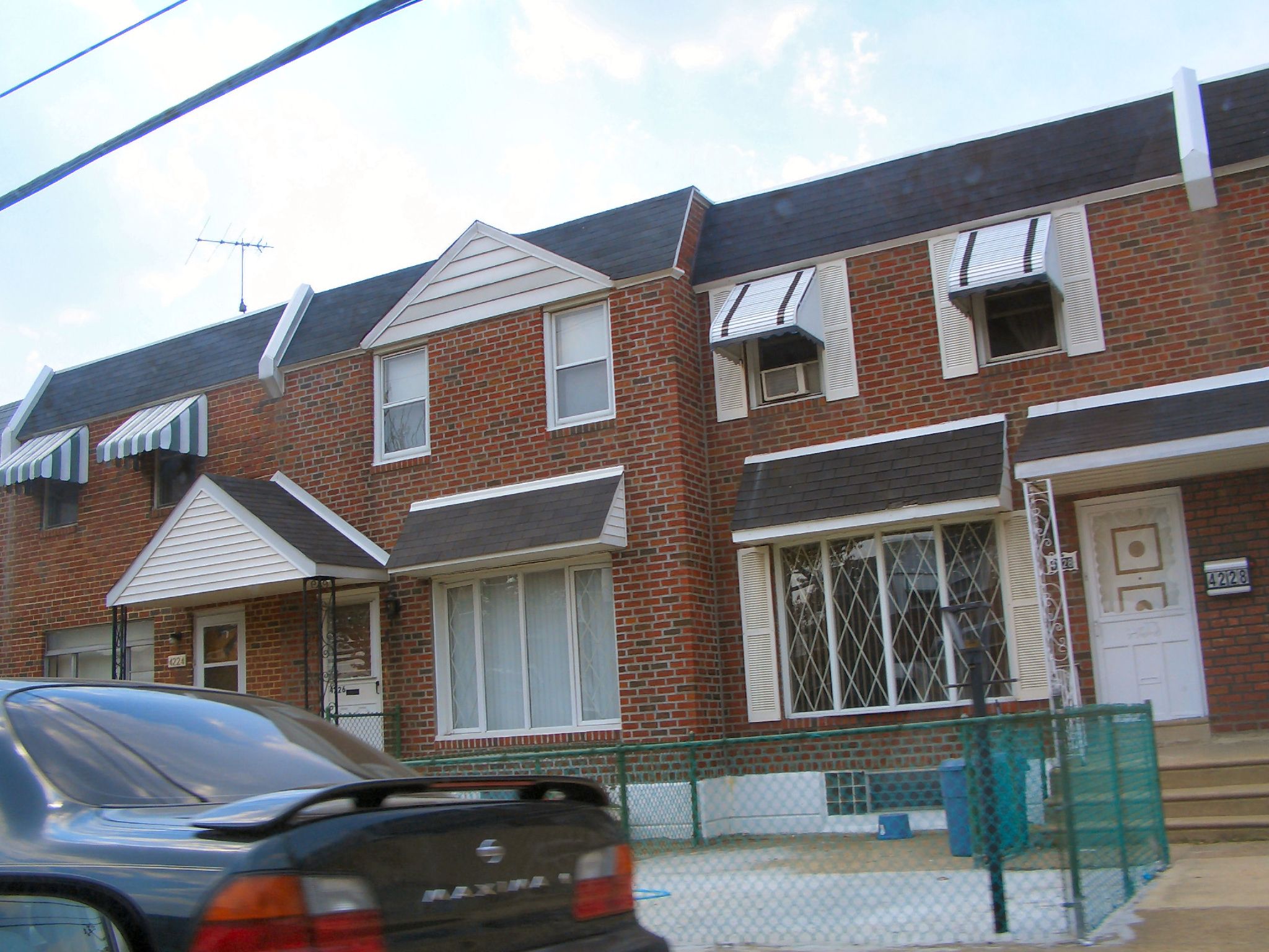 an automobile is parked outside a four - story apartment