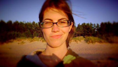 a woman wearing glasses standing on a beach