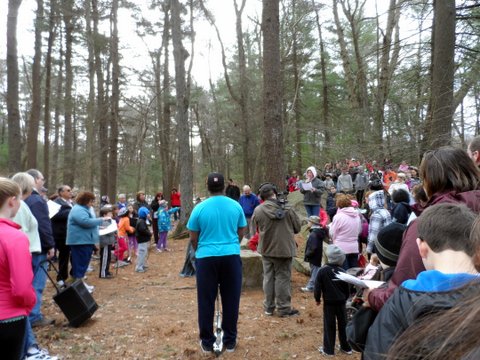 a crowd of people standing in a forest holding cell phones